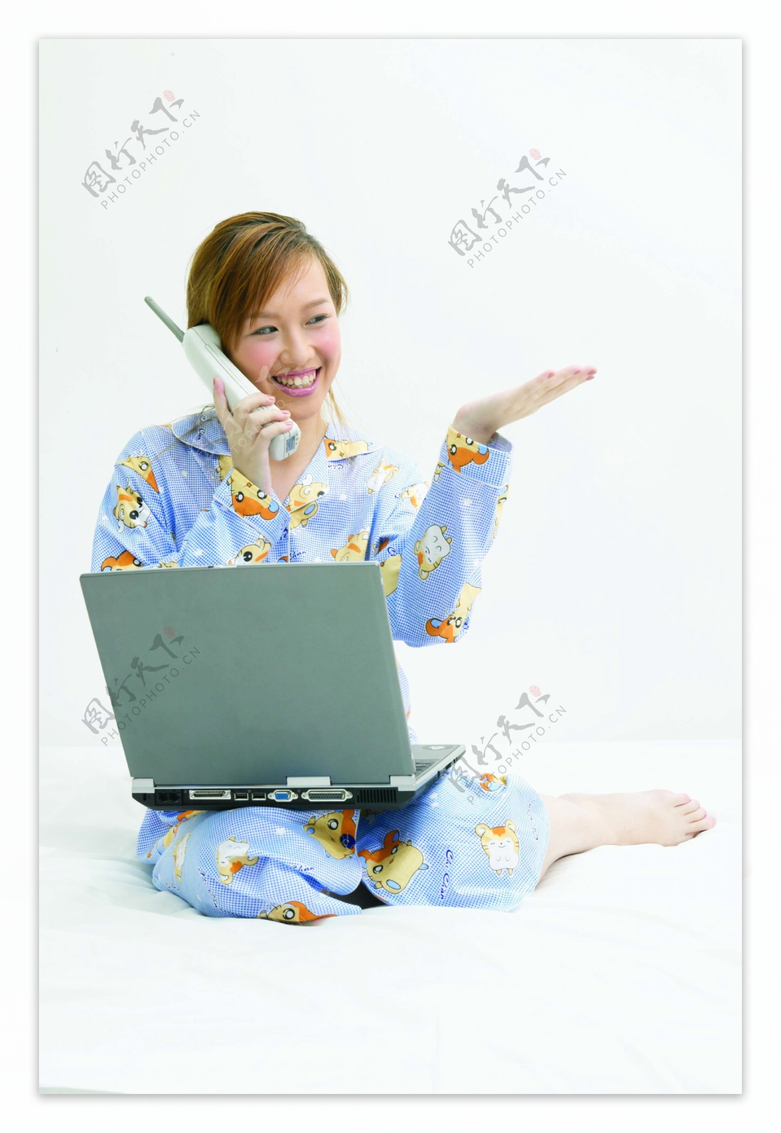 坐在床上打电话玩电脑的睡衣女人图片