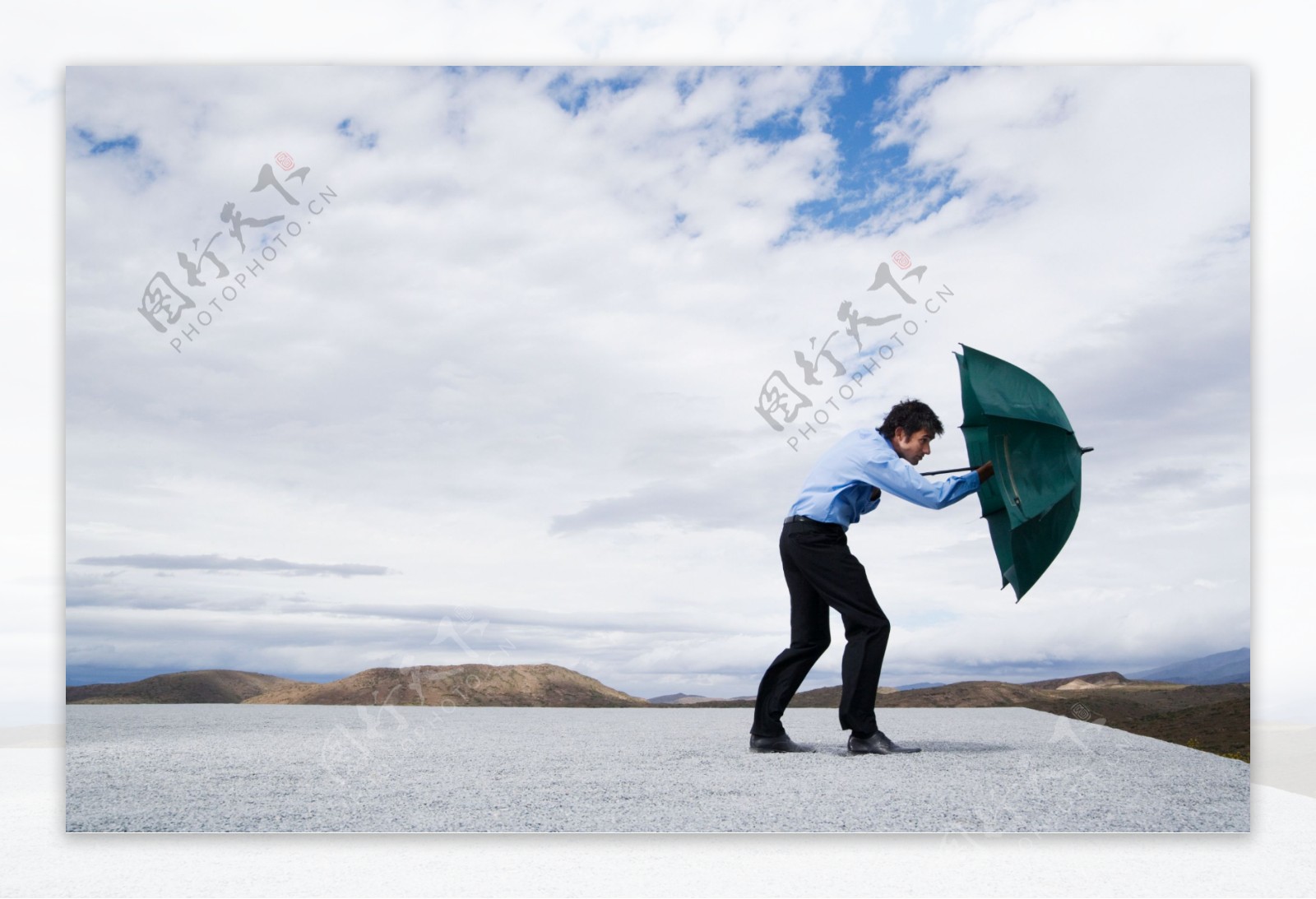 用伞挡风的男人图片