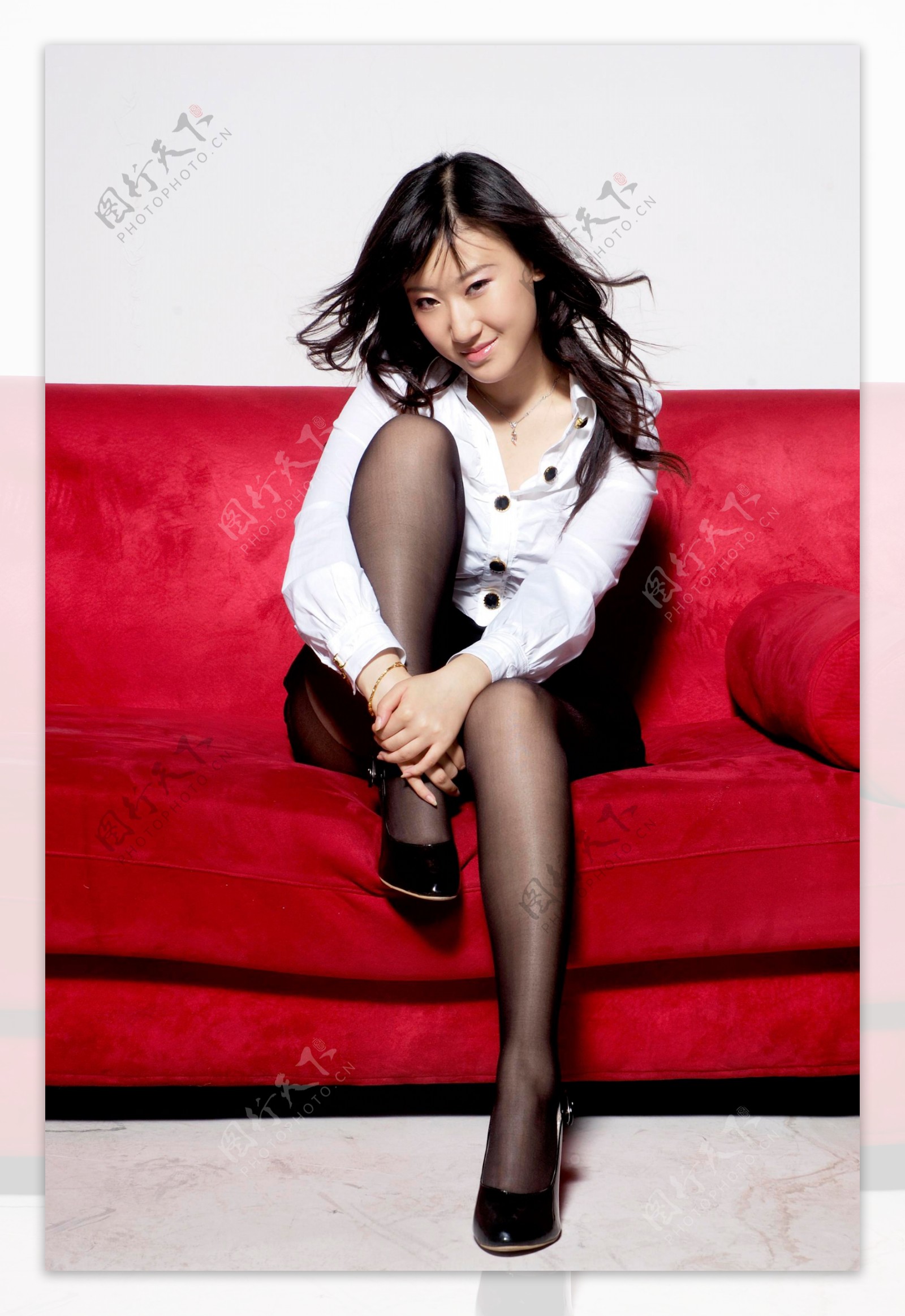 坐在红色沙发上的时尚美女图片