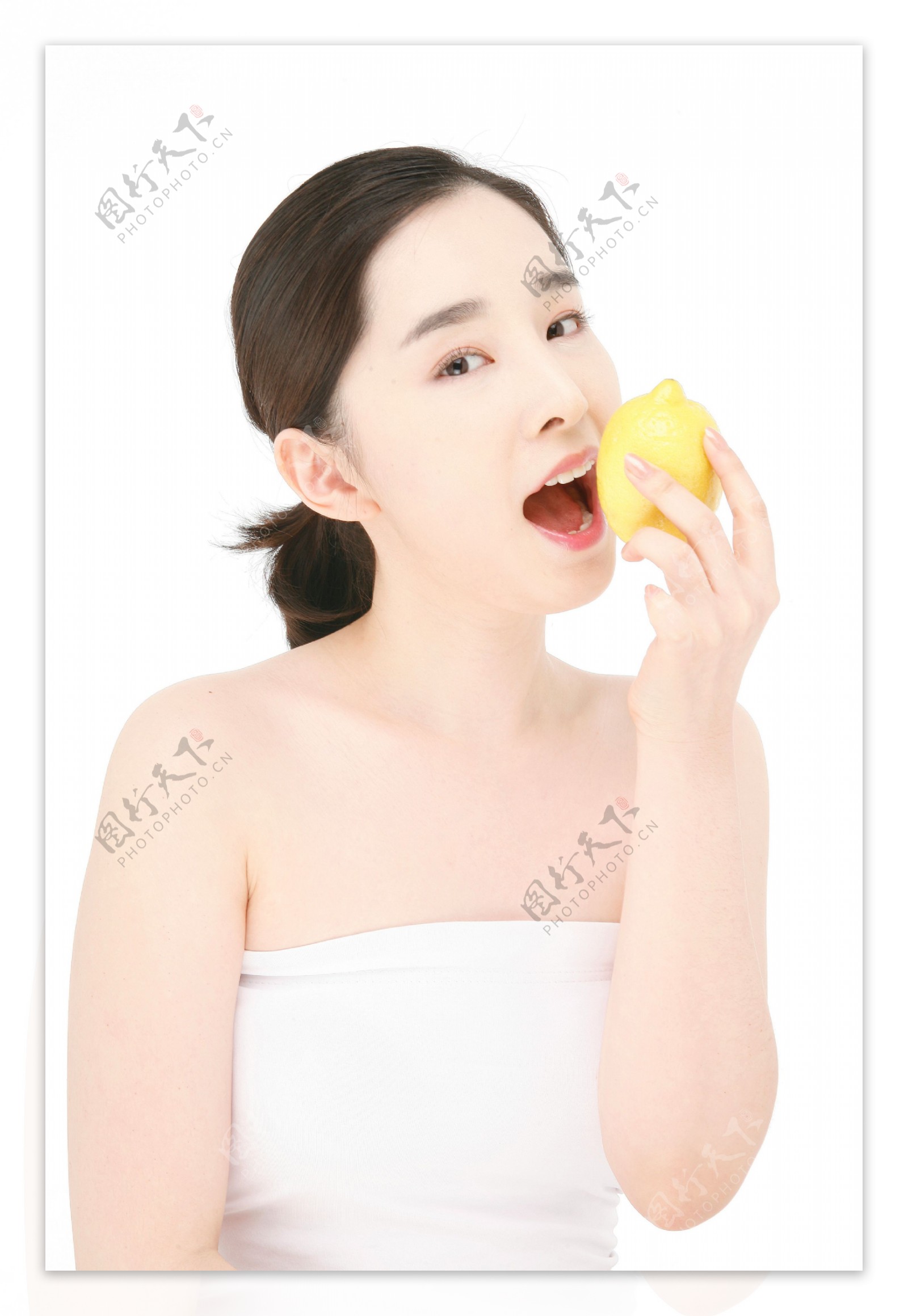 张嘴去咬手里柠檬的漂亮女孩图片图片