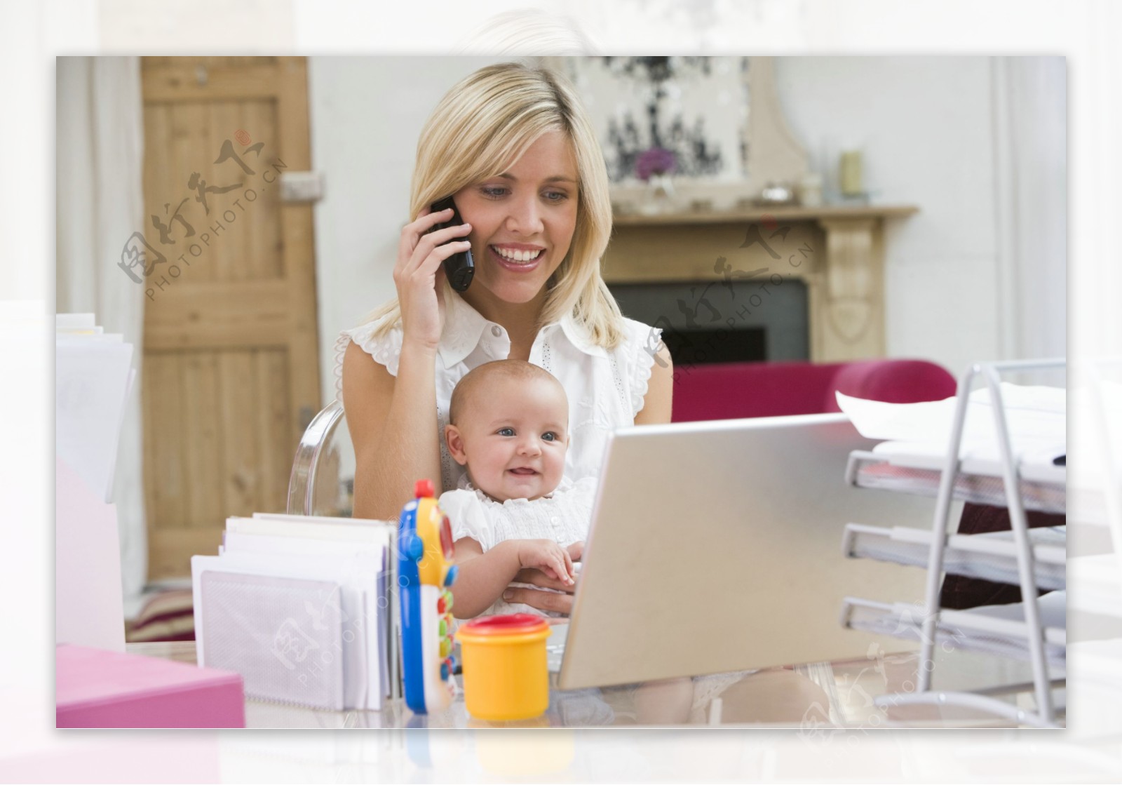 抱着宝宝坐在电脑前打电话的外国女性图片图片