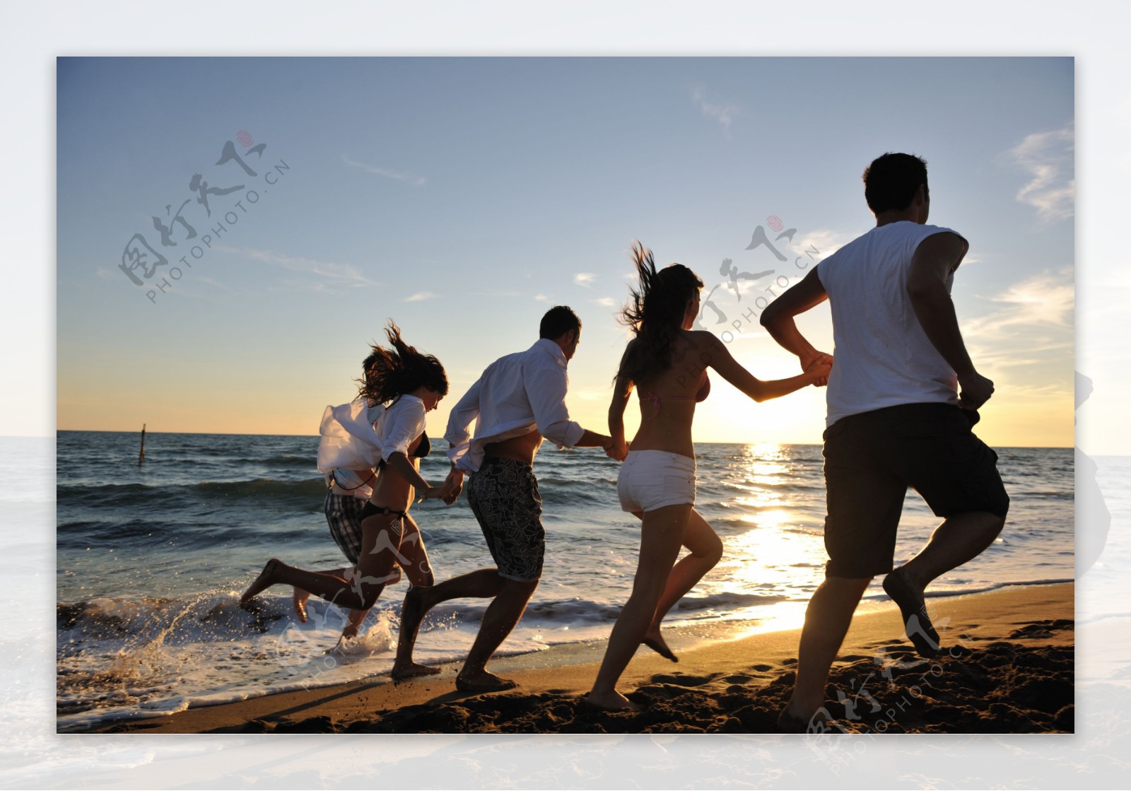 手拉手沙滩上跑步的年轻人图片