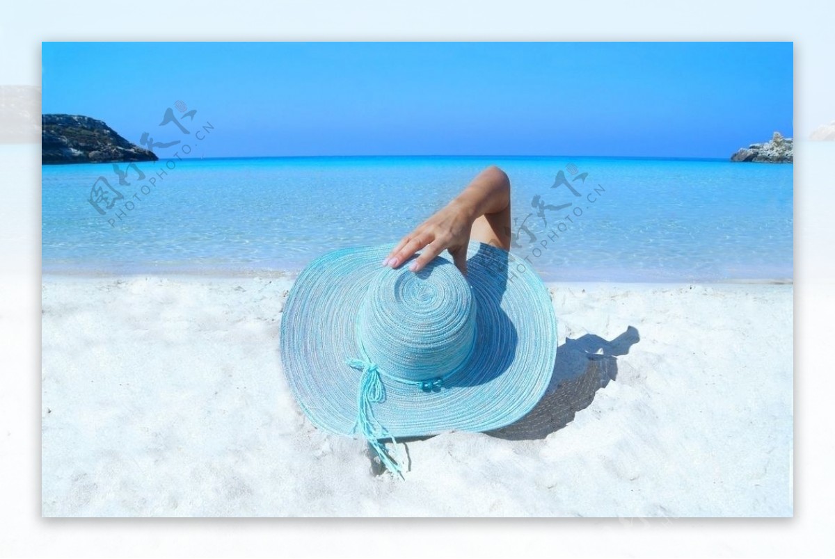 戴着蓝色草帽躺在海滩上