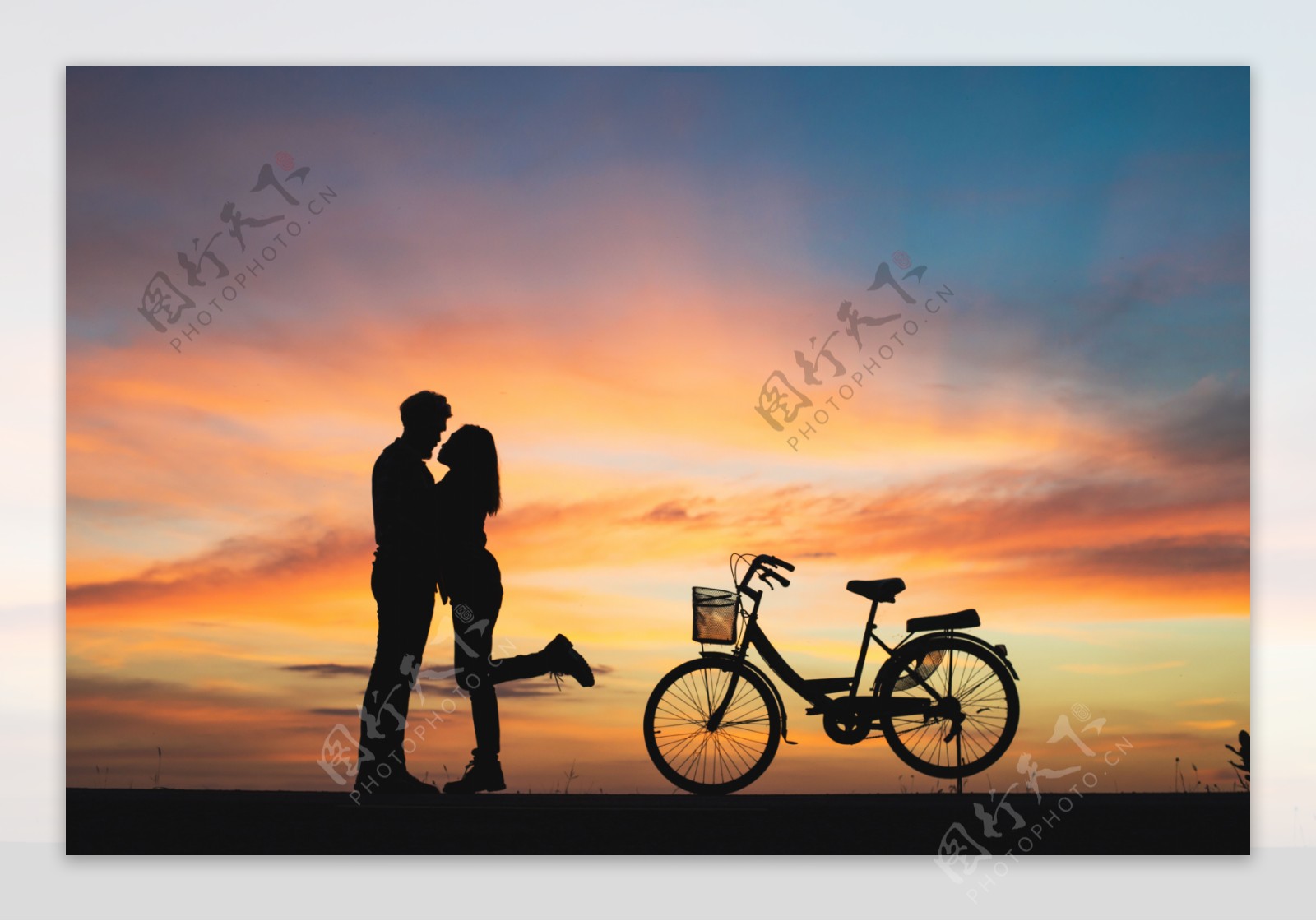 情侣与自行车在夕阳下的剪影